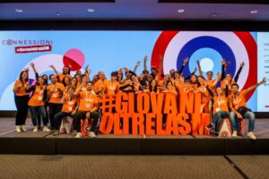 Gruppone di Ragazzi esultanti sul palco di #GiovanioltrelaSM 2022 - Connessioni. Alzano le braccia festanti dietro a critta grande in polistirolo #giovanioltrelasm