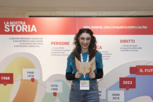 una ragazza sorridenti legge un opuesocolo a #GiovanioltrelaSM - Tempo